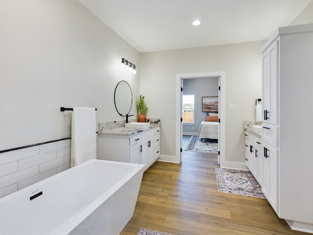 bathroom with a washtub, vanity, and hardwood / wood-style flooring