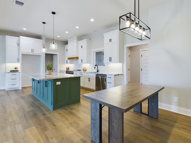 kitchen featuring dishwasher, white cabinetry, a center island, light stone countertops, and decorative light fixtures