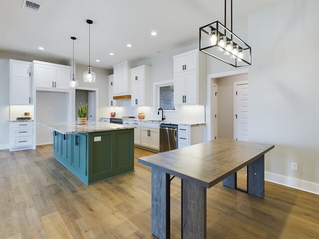 kitchen featuring dishwasher, white cabinetry, a center island, light stone countertops, and decorative light fixtures