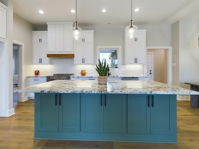 kitchen featuring a spacious island, light stone countertops, hanging light fixtures, and white cabinets