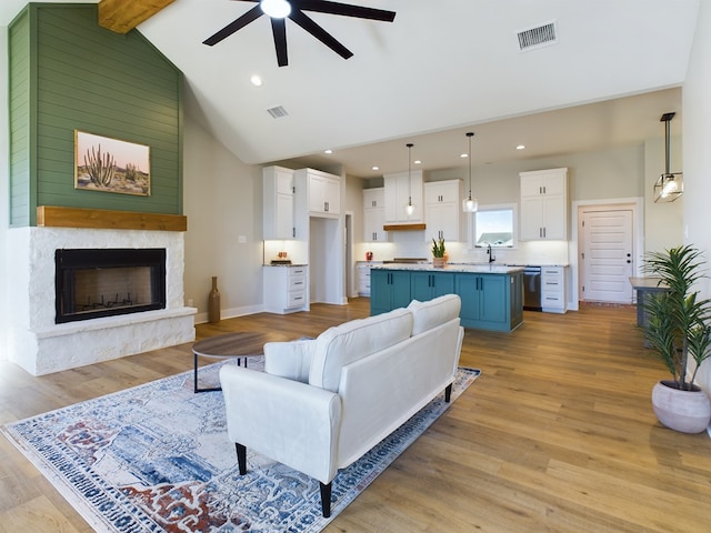 living room with vaulted ceiling with beams, light hardwood / wood-style floors, sink, and ceiling fan