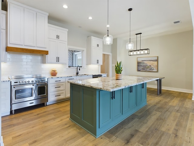 kitchen featuring pendant lighting, white cabinetry, double oven range, light stone counters, and a kitchen island