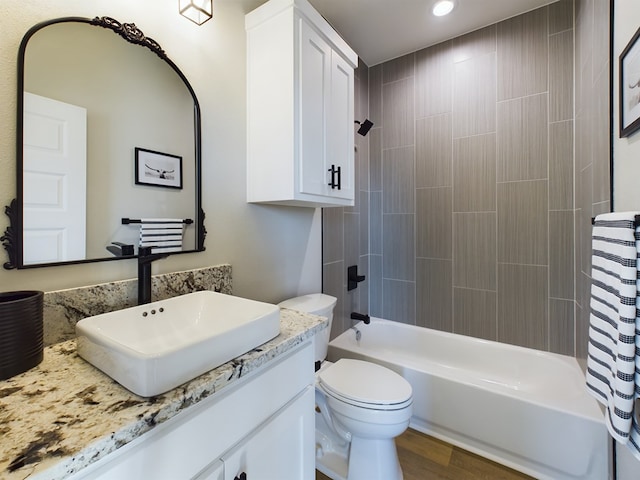 full bathroom featuring tiled shower / bath, vanity, toilet, and hardwood / wood-style floors