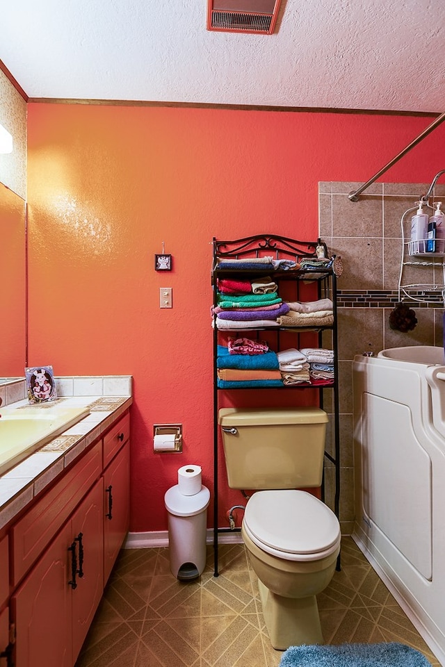 bathroom featuring vanity, toilet, tile patterned flooring, and a textured ceiling