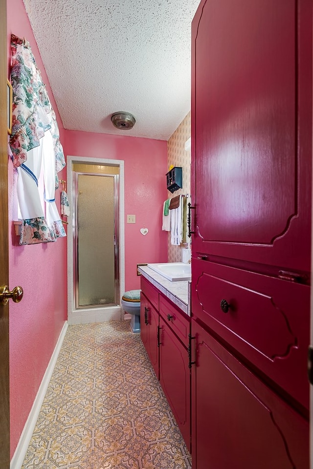 bathroom featuring a shower with door, vanity, a textured ceiling, and toilet