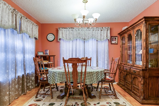 dining space with plenty of natural light, a chandelier, light hardwood / wood-style floors, and a textured ceiling