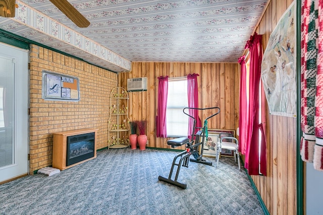 workout area with a brick fireplace, wooden walls, a wall mounted AC, and carpet