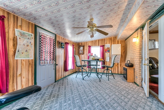 dining area with ceiling fan, lofted ceiling, wooden walls, and carpet