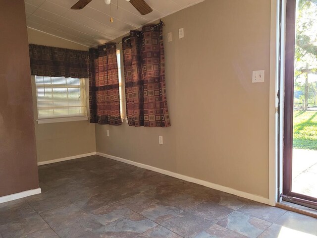 empty room featuring ceiling fan, lofted ceiling, and a wealth of natural light