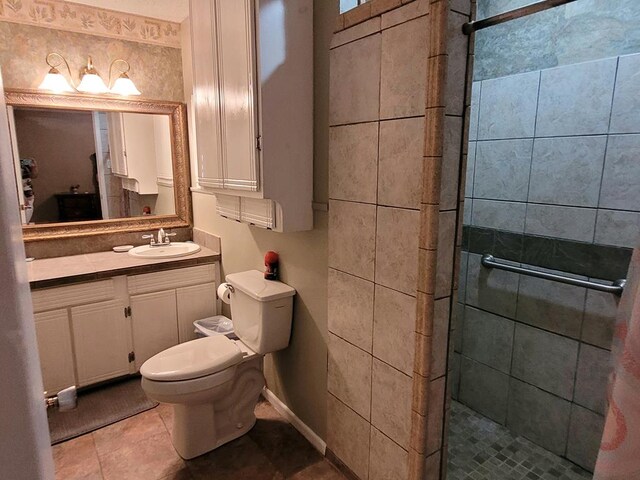 bathroom with tile patterned flooring, vanity, a shower with shower door, and toilet