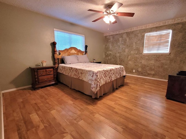 bedroom with a textured ceiling, light hardwood / wood-style floors, and ceiling fan