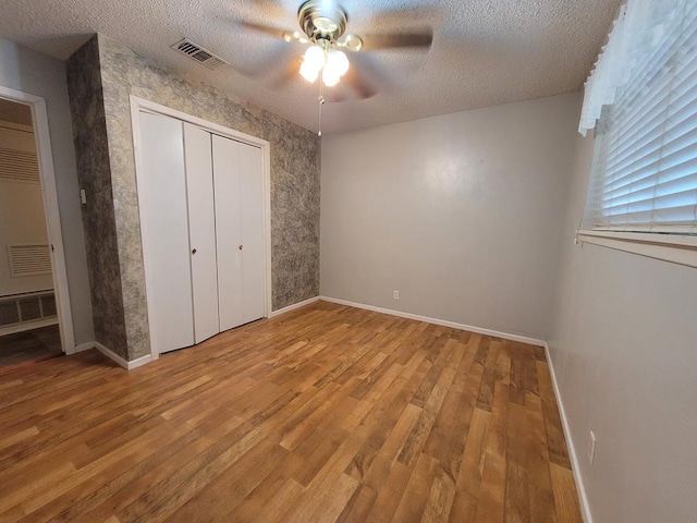 unfurnished bedroom with light wood-type flooring, a textured ceiling, and ceiling fan