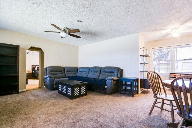 living room with ceiling fan, carpet floors, and a textured ceiling