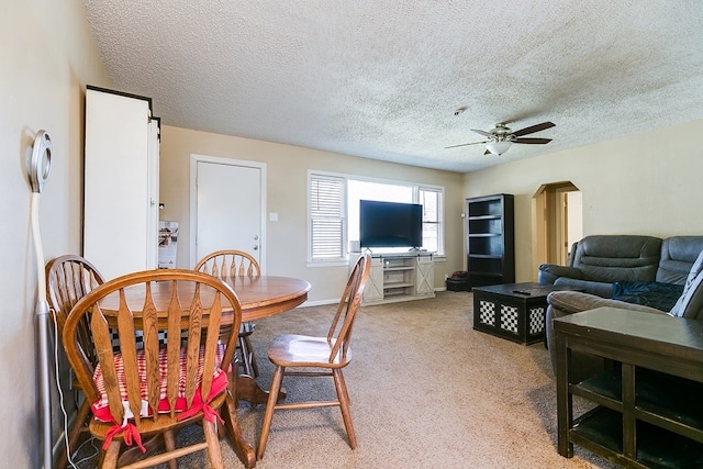 carpeted dining area featuring ceiling fan and a textured ceiling