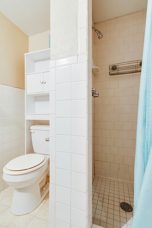 bathroom featuring toilet, a shower with shower curtain, and tile walls