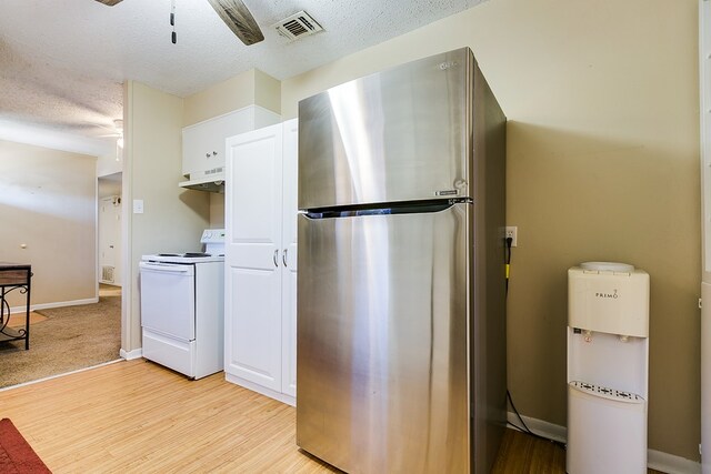 kitchen with stainless steel refrigerator, white electric stove, white cabinetry, ceiling fan, and light hardwood / wood-style flooring