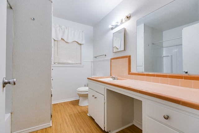 bathroom with hardwood / wood-style flooring, vanity, decorative backsplash, toilet, and walk in shower