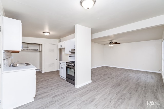 kitchen with sink, light hardwood / wood-style flooring, black gas range oven, ceiling fan, and white cabinets