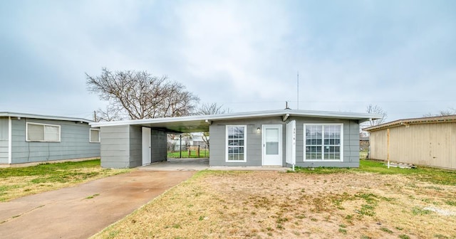 back of property featuring a carport and a lawn