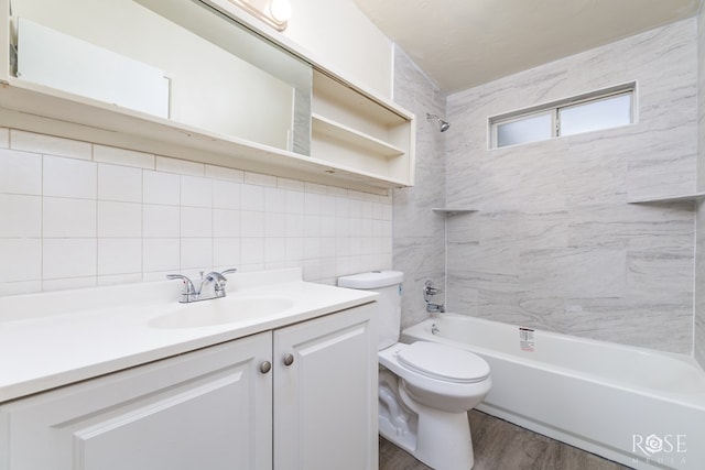 full bathroom with hardwood / wood-style floors, backsplash, tiled shower / bath combo, vanity, and toilet