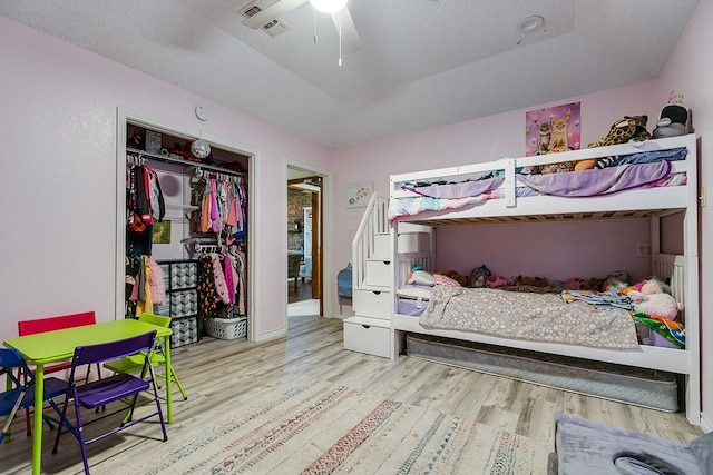 bedroom with visible vents, a textured ceiling, wood finished floors, a closet, and ceiling fan