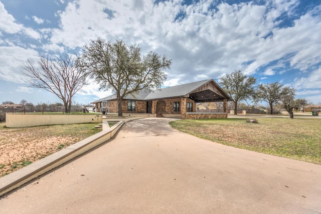 view of front of property with brick siding, concrete driveway, a front lawn, and fence