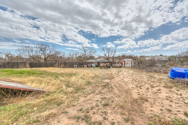 view of yard featuring a storage shed, an outdoor structure, and fence