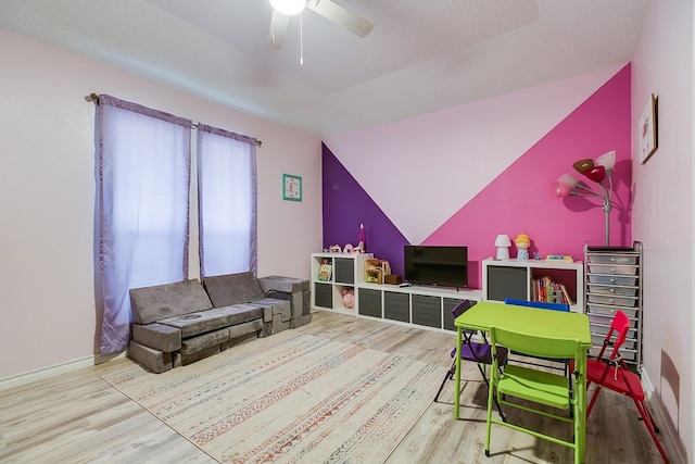 recreation room featuring a ceiling fan, lofted ceiling, wood finished floors, and baseboards