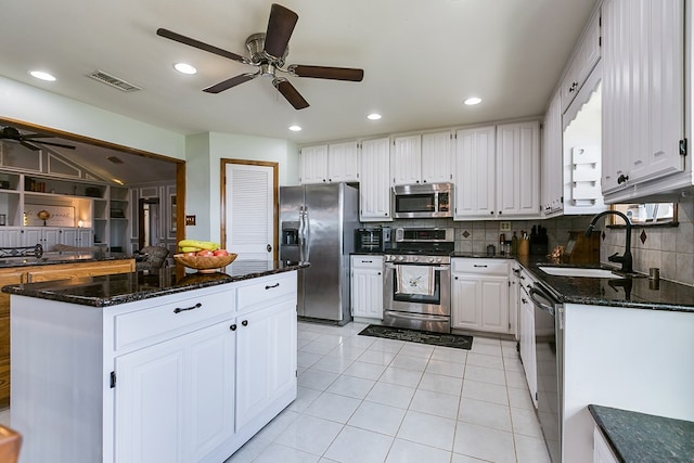 kitchen featuring visible vents, a sink, dark stone counters, appliances with stainless steel finishes, and light tile patterned floors