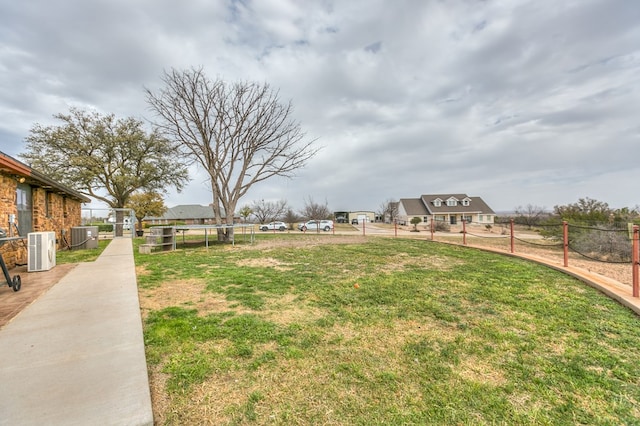 view of yard with a trampoline, fence, and central AC