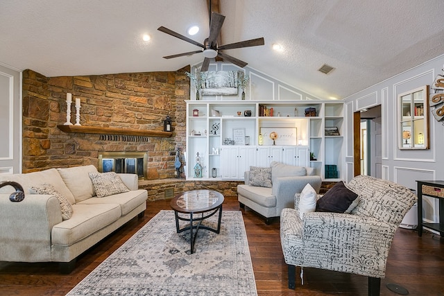 living area featuring visible vents, a textured ceiling, dark wood-style floors, a stone fireplace, and vaulted ceiling