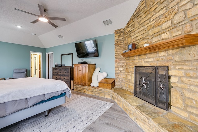 bedroom featuring lofted ceiling, wood finished floors, visible vents, and a textured ceiling