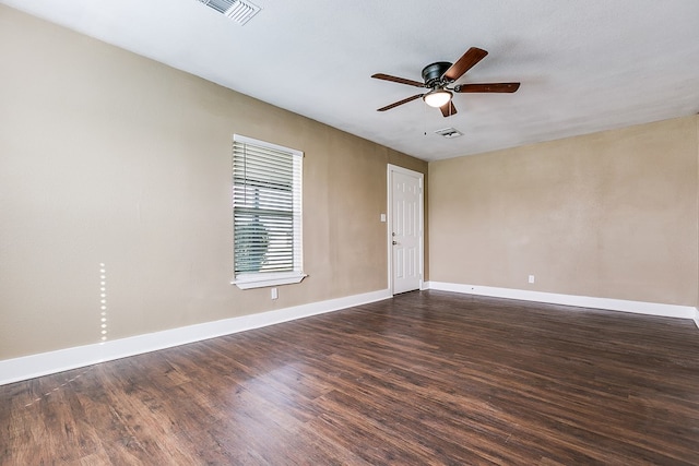 spare room featuring dark wood-type flooring, visible vents, and baseboards