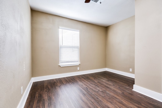 spare room featuring dark wood-style floors, baseboards, and a ceiling fan