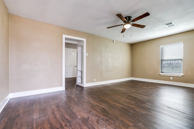 empty room with dark wood-style flooring, visible vents, a ceiling fan, a textured ceiling, and baseboards