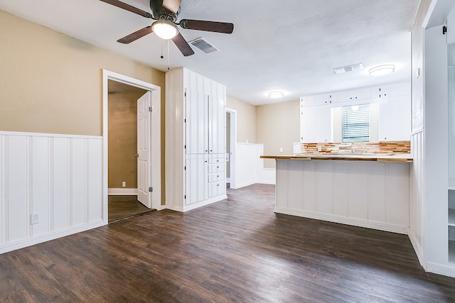 kitchen featuring a peninsula, dark wood-type flooring, visible vents, and white cabinets