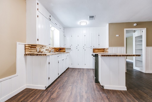 kitchen with a peninsula, visible vents, and white cabinets