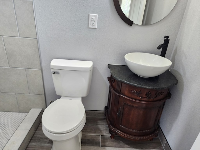 bathroom featuring vanity, toilet, and a tile shower