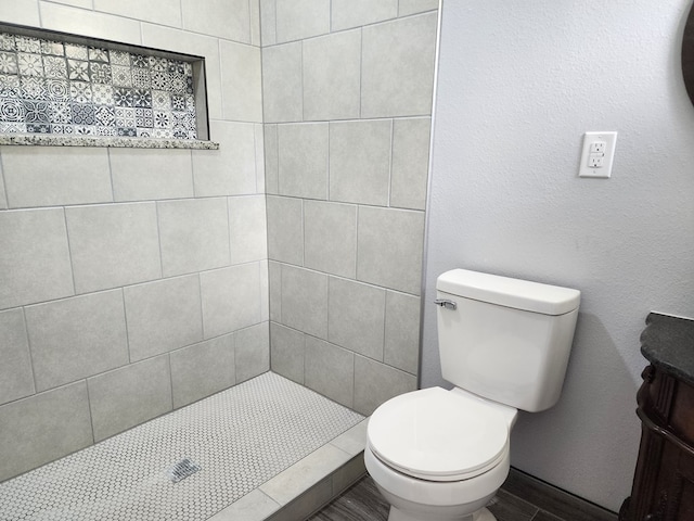 bathroom with tiled shower and toilet