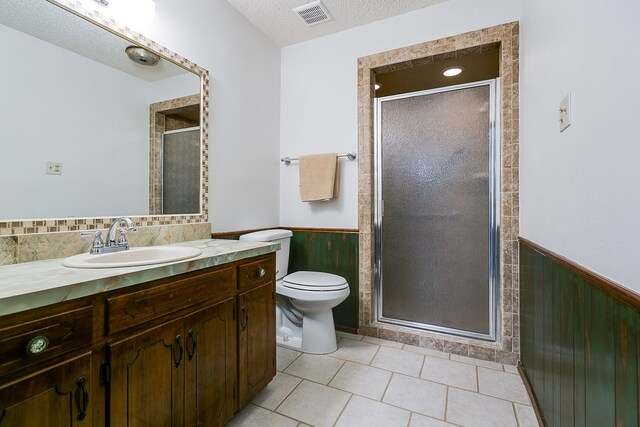 4302 Homestead Cir, Wall, TX 76903 - full bathroom with wainscoting, a stall shower, toilet, a textured ceiling, and vanity