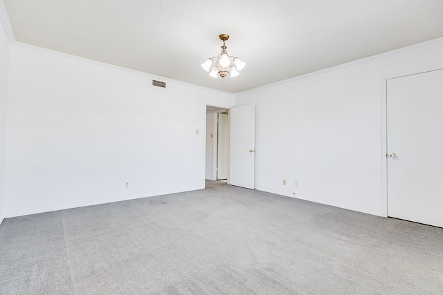 spare room featuring an inviting chandelier, crown molding, carpet floors, and a textured ceiling