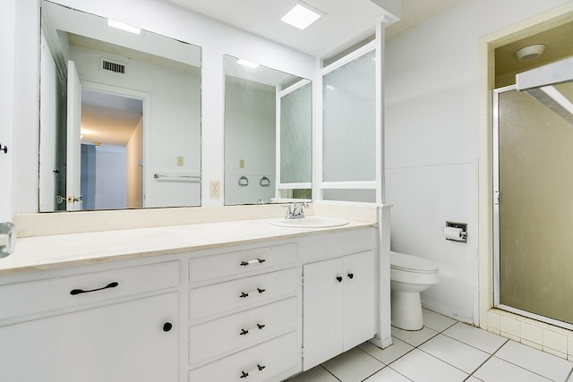 bathroom with tile patterned flooring, vanity, toilet, and walk in shower