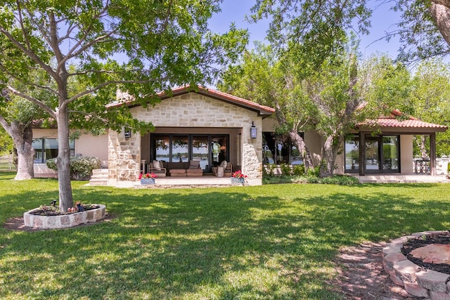 rear view of house featuring a yard, stone siding, and stucco siding