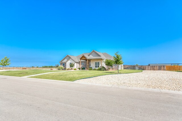view of front of property featuring fence, a front lawn, and stone siding