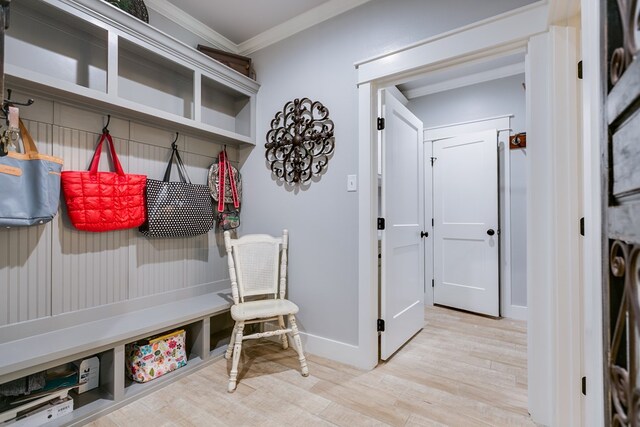 mudroom featuring baseboards, ornamental molding, and light wood finished floors