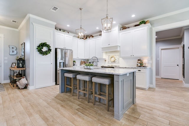 kitchen with an island with sink, a breakfast bar, light wood finished floors, visible vents, and recessed lighting
