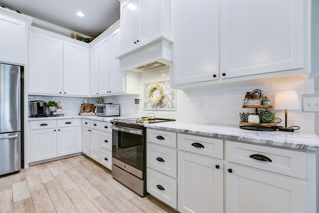kitchen featuring a toaster, white cabinetry, decorative backsplash, light stone counters, and appliances with stainless steel finishes