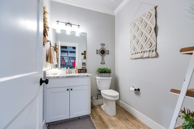 bathroom featuring wood finished floors, vanity, baseboards, toilet, and ornamental molding