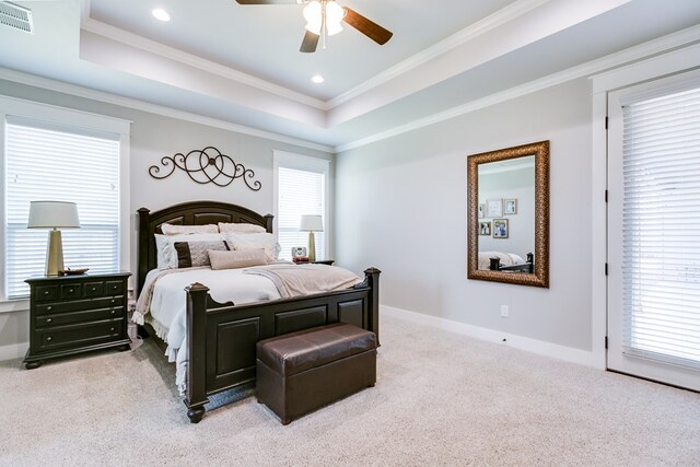 bedroom with a raised ceiling, baseboards, visible vents, light colored carpet, and ornamental molding