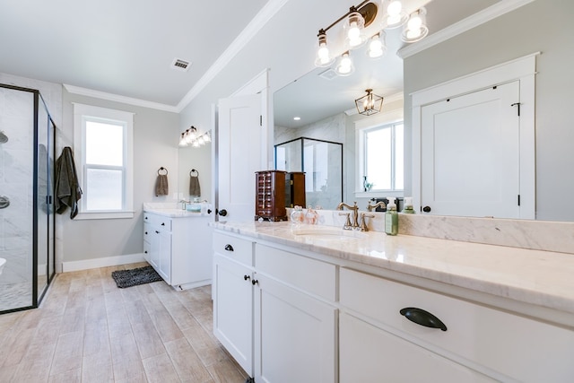 full bathroom with wood finished floors, a stall shower, ornamental molding, two vanities, and visible vents